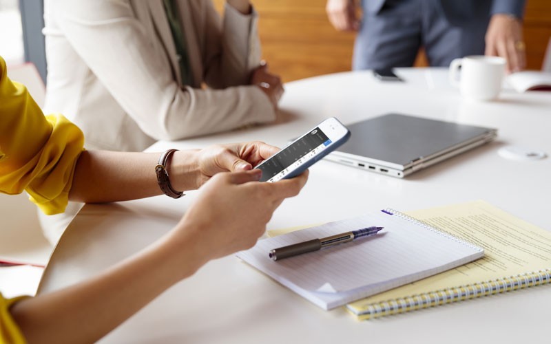 Vrouw in vergadering werkt met een smartphone