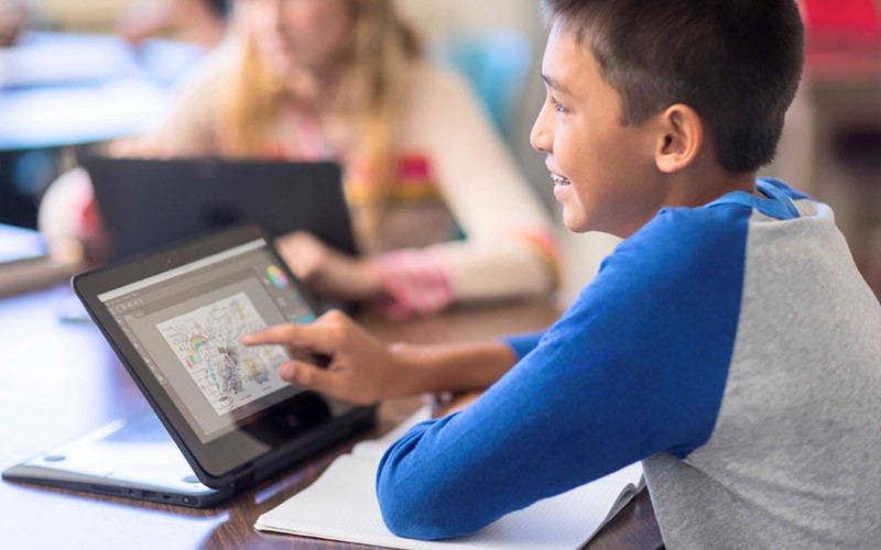 Een jonge leerling werkt op een HP touch screen laptop