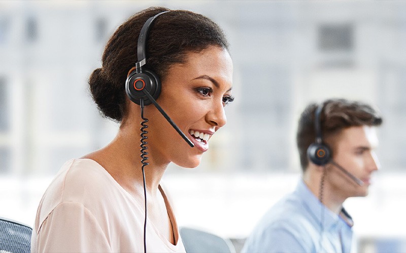 Een glimlachende vrouw gebruikt een Evolve headset