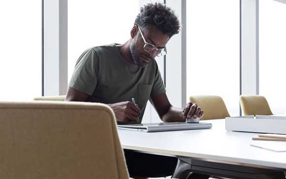 Een jonge man werkt met een Microsoft Surface  Laptop