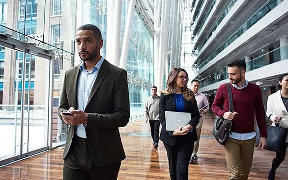 Zakenmensen lopen door een gebouw met Microsoft devices