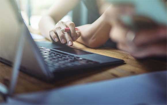 Een vrouw gebruikt haar trackpad op een laptop