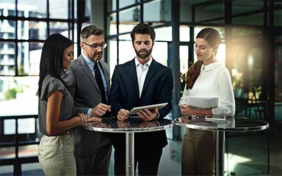 Collega's staan om een ronde tafel met hun tablet