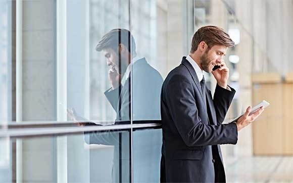 Zakenman buiten het gebouw met een mobiele telefoon en tablet