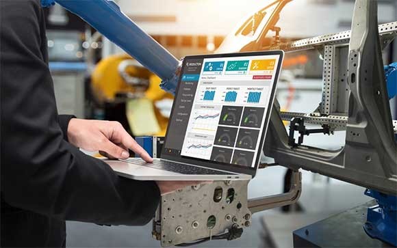 Een man met een laptop in een autofabriek